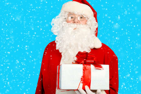 Portrait of Santa Claus with present over blue background. Christmas.の写真素材