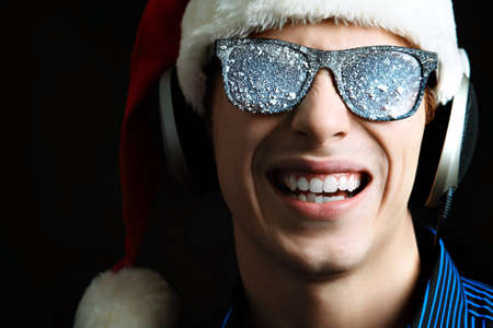 Portrait of a funny young man in Santa Claus hat and headphones. Christmas.の写真素材