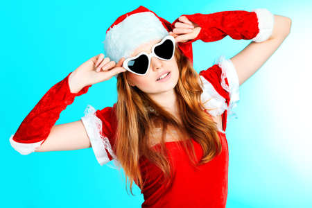 Beautiful young woman in Santa Claus clothes over blue background.の写真素材