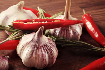 Fresh garlic with red pepper and rosemary on a table.の写真素材