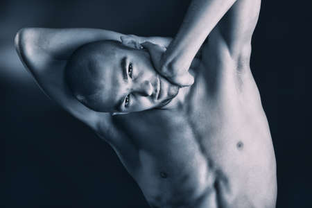 Portrait of a handsome muscular man posing over black background.の写真素材