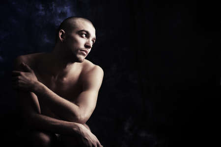 Portrait of a handsome muscular man posing over black background.の写真素材