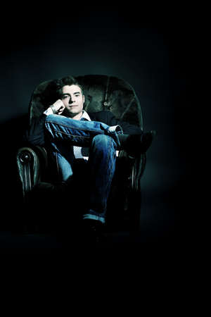 Portrait of a handsome young man posing over black background.の写真素材