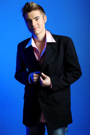 Young man dressed in rock'n'roll style, posing over blue background.の写真素材