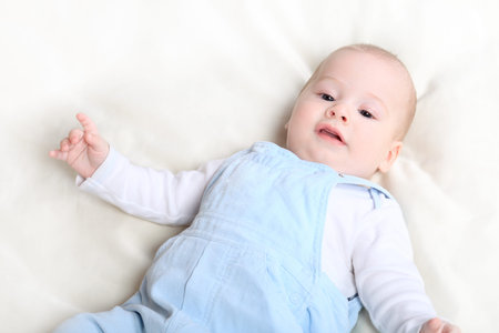 Beautiful baby is lying in a bed.