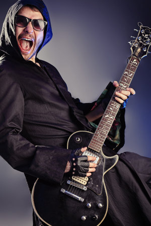 Heavy metal musician  is playing electrical guitar. Shot in a studio.