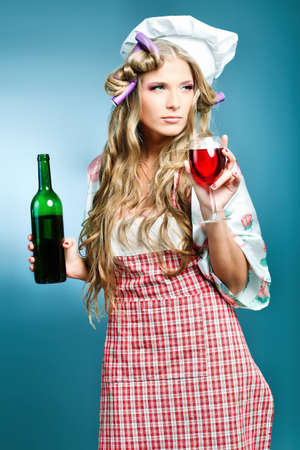 Portrait of a young woman cook holding a wine. Shot in a studio over grey background.の写真素材
