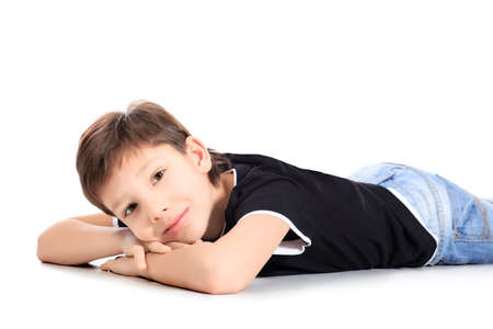 Portrait of a happy 9 year boy lying on a floor. Isolated over white background.の写真素材
