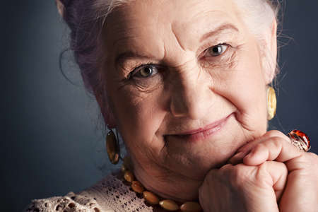 Portrait of a smiling senior woman. Studio shot over grey background.の写真素材