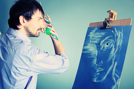 Portrait of an artist painting on easel. Shot in a studio.の写真素材