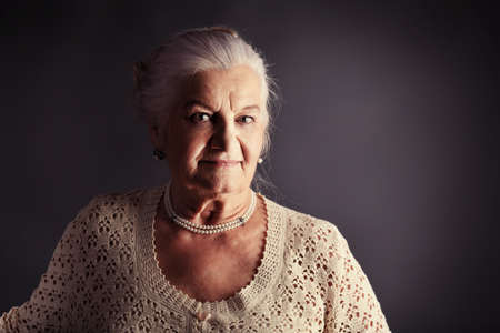 Portrait of a smiling senior woman. Studio shot over grey background.の写真素材
