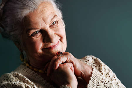 Portrait of a smiling senior woman. Studio shot over grey background.の写真素材