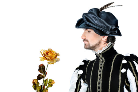 Portrait of a handsome man grandee in 16th century costume holding golden rose. Isolated over white background.の写真素材