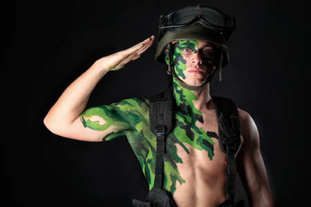 Shot of a conceptual soldier painted in khaki colors. Studio shot over black background.の写真素材