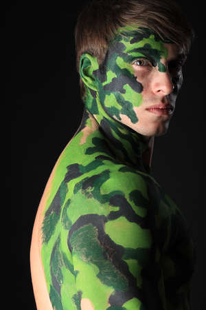 Shot of a conceptual soldier painted in khaki colors. Studio shot over black background.の写真素材