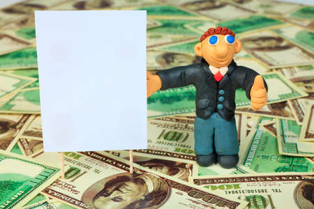 Shot of a plasticine businessman in a suit. Over money background.の写真素材