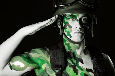 Shot of a conceptual soldier painted in khaki colors. Studio shot over black background.