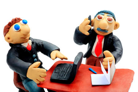 Shot of two plasticine businessmen working at the office. Isolated over white background.の写真素材