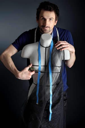 Portrait of a man fashion designer working with dummy at studio.の写真素材