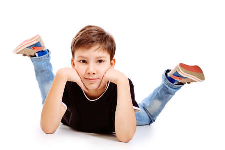 Portrait of a happy 9 year boy lying on a floor. Isolated over white background.の写真素材