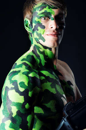 Shot of a conceptual soldier painted in khaki colors. Studio shot over black background.の写真素材