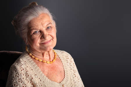 Portrait of a smiling senior woman. Studio shot over grey background.の写真素材