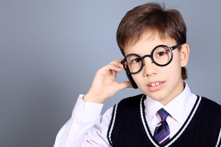 Educational theme: portrait of a schoolboy. Studio shot over grey background.