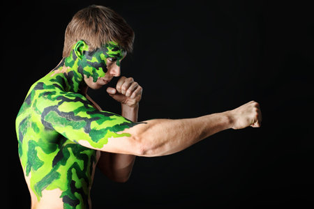 Shot of a conceptual soldier painted in khaki colors. Studio shot over black background.の写真素材