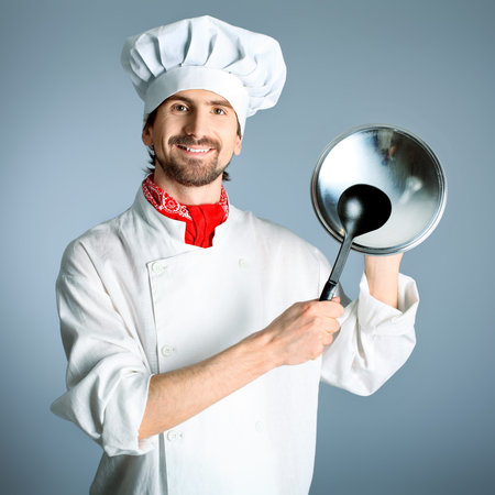 Portrait of a man cook holding a saucepan and ladle. Shot in a studio over grey background.