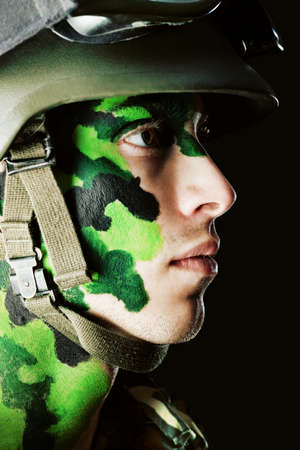 Shot of a conceptual soldier painted in khaki colors. Studio shot over black background.の写真素材
