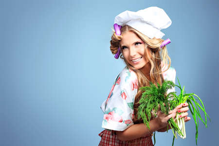 Beautiful blonde woman housewife holding greens and fruits. Studio shot over grey background.の写真素材
