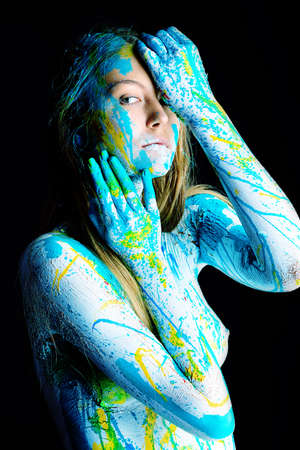 Art project: beautiful woman painted with many vivid colors. Over black background.の写真素材