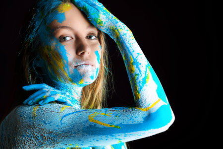 Art project: beautiful woman painted with many vivid colors. Over black background.