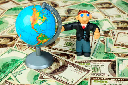 Shot of a plasticine businessman in a suit. Over money background.の写真素材