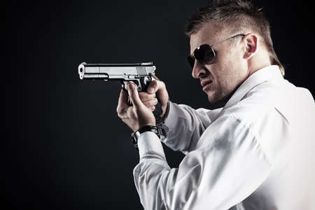 Portrait of a handsome man holding a gun. Studio shot.の写真素材