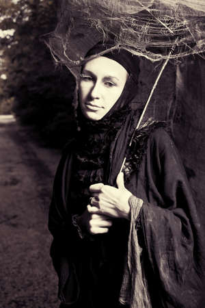 Shot of a sad woman in mask wearing old-fashioned  black dress. の写真素材