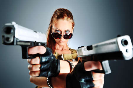 Shot of a sexy military woman posing with guns.の写真素材