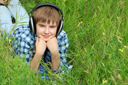 Portrait of a happy boy teenager with headphones outdoors.の写真素材