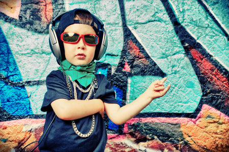 Portrait of a trendy little boy  with headphones outdoors.