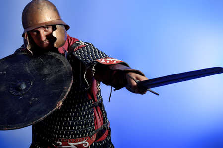 Portrait of a medieval male knight in armor over blue background.の写真素材