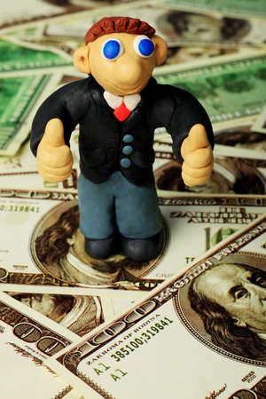 Shot of a plasticine businessman in a suit. Over money background.の写真素材