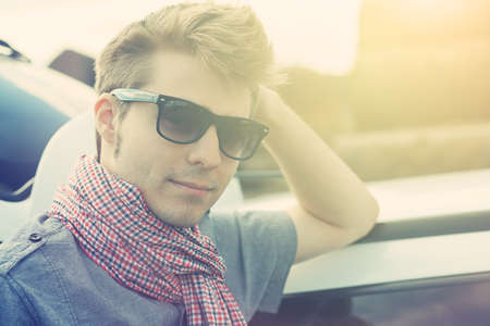 Handsome young man having summer trip on a car.の写真素材