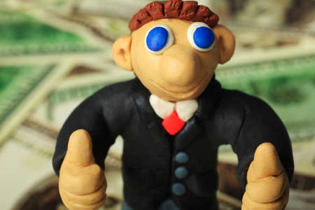 Shot of a plasticine businessman in a suit. Over money background.の写真素材