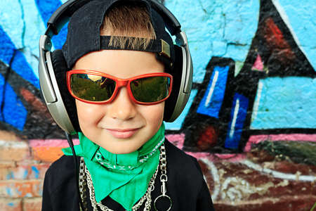 Portrait of a trendy little boy  with headphones outdoors.の写真素材