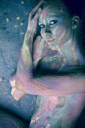 Portrait of an artistic woman painted in metal style. Shot in a studio.