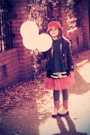 Shot of a cute girl walking with balloons at the park.の写真素材
