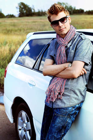 Handsome young man having summer trip on a car.の写真素材