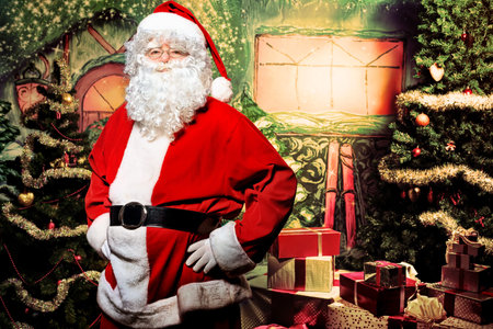 Santa Claus posing with presents over Christmas background.
