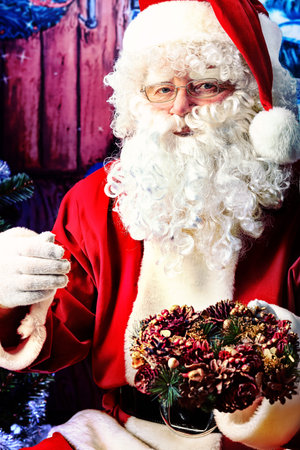 Santa Claus posing with presents over Christmas background.