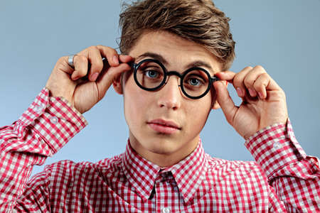 Portrait of a funny young man in spectacles. Over grey background.の写真素材